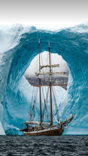 在丹麦格陵兰岛斯科斯比湾冰拱道航行的老帆船