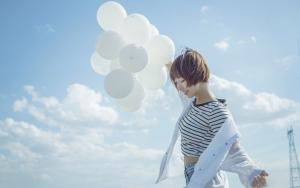蓝天白云下拿白色气球的开朗少女活力写真