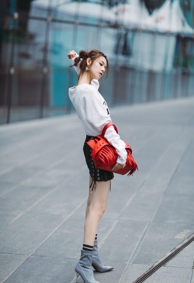 演员陈瑶白色卫衣混搭机车皮裙手持红包街头范写真图片